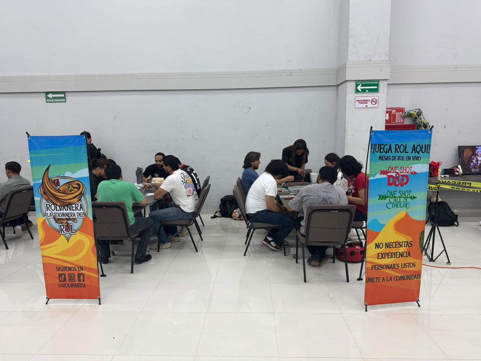 Mesas de rol de Rolvanera durante un evento con banners de la comunidad